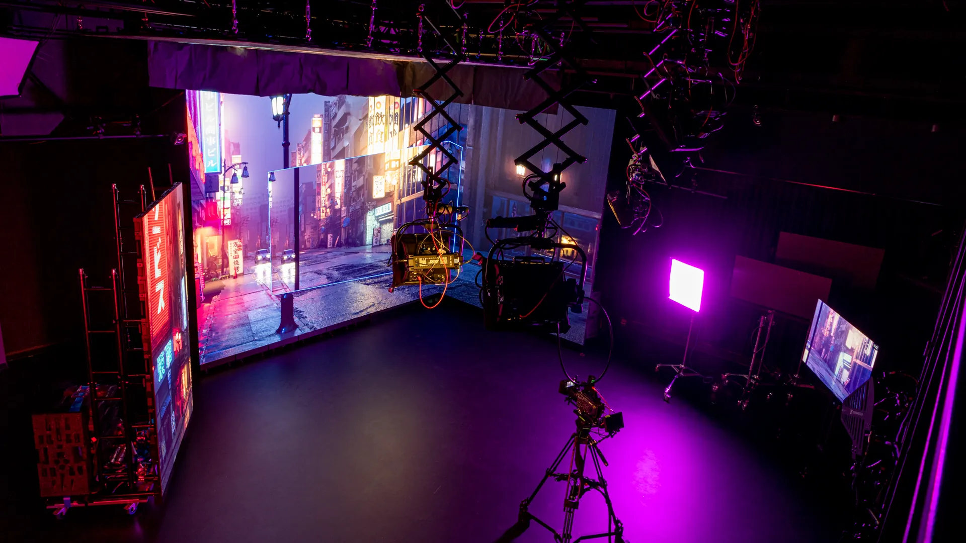 The LED stage in our XR Lab, with a neon street on the walls, a cinema camera and coloured practical lights