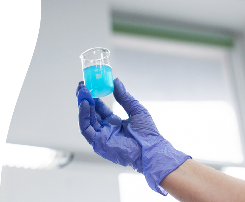 Image depicting a lab worker holding up a vial of blue liquid.