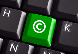 Close-up of a black keyboard with a green key featuring a white copyright symbol between the H and K keys.