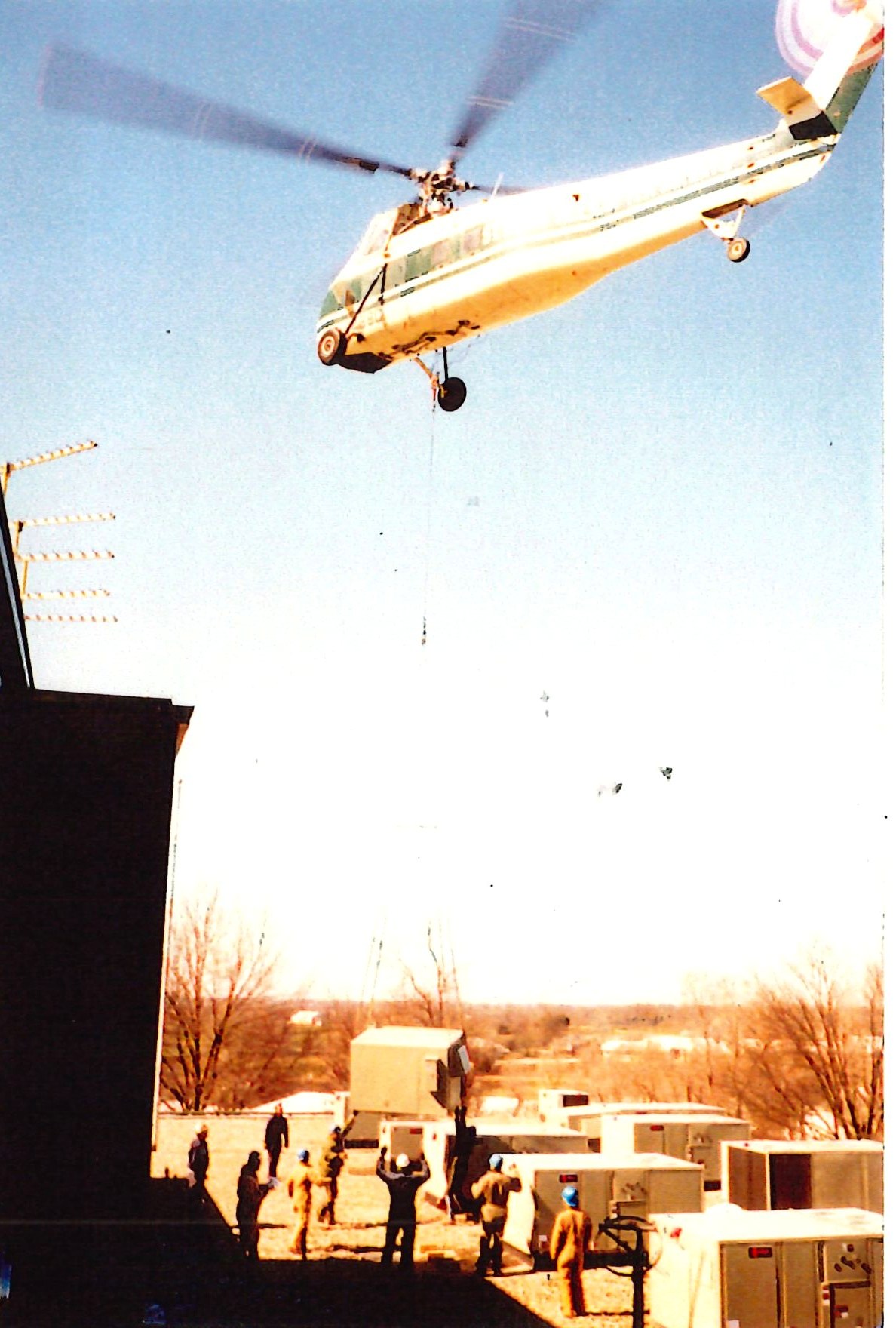 Helicopter lifting rooftop mechanical units onto a building