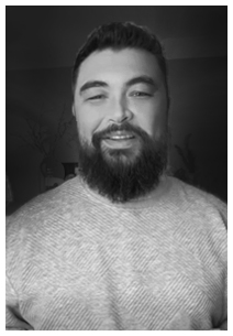 Smiling man with dark hair and beard wearing a light-colored sweater against a dark background.
