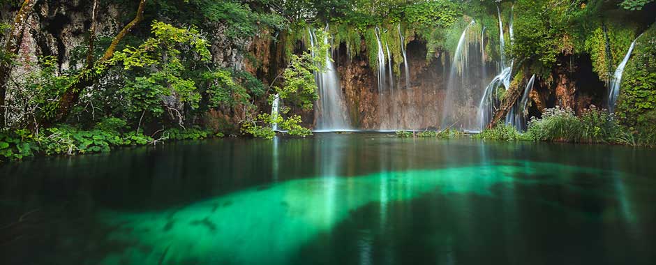 Sonnenlicht über den Wasserfällen der Plitvicer Seen, wo türkisfarbenes Wasser über Kalksteinterrassen fließt