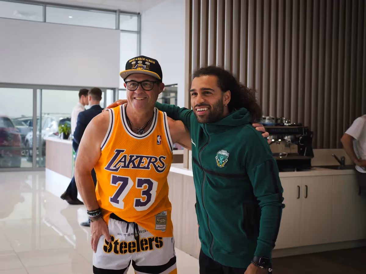 person in cap with yellow nba jersey gets photo with jack jumpers player