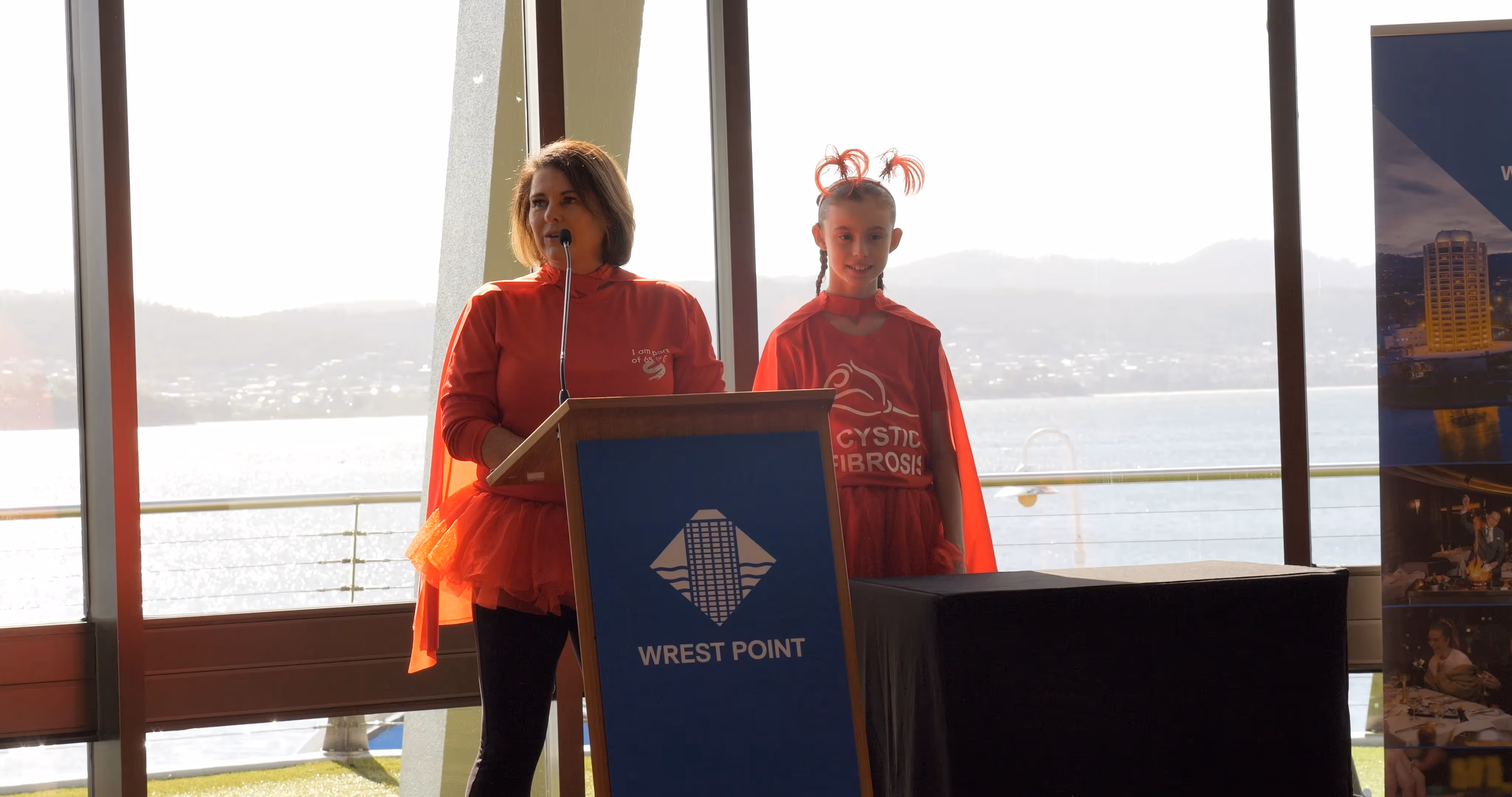 lady and girl in red cystic fibrosis t-shirts standing at lecturn