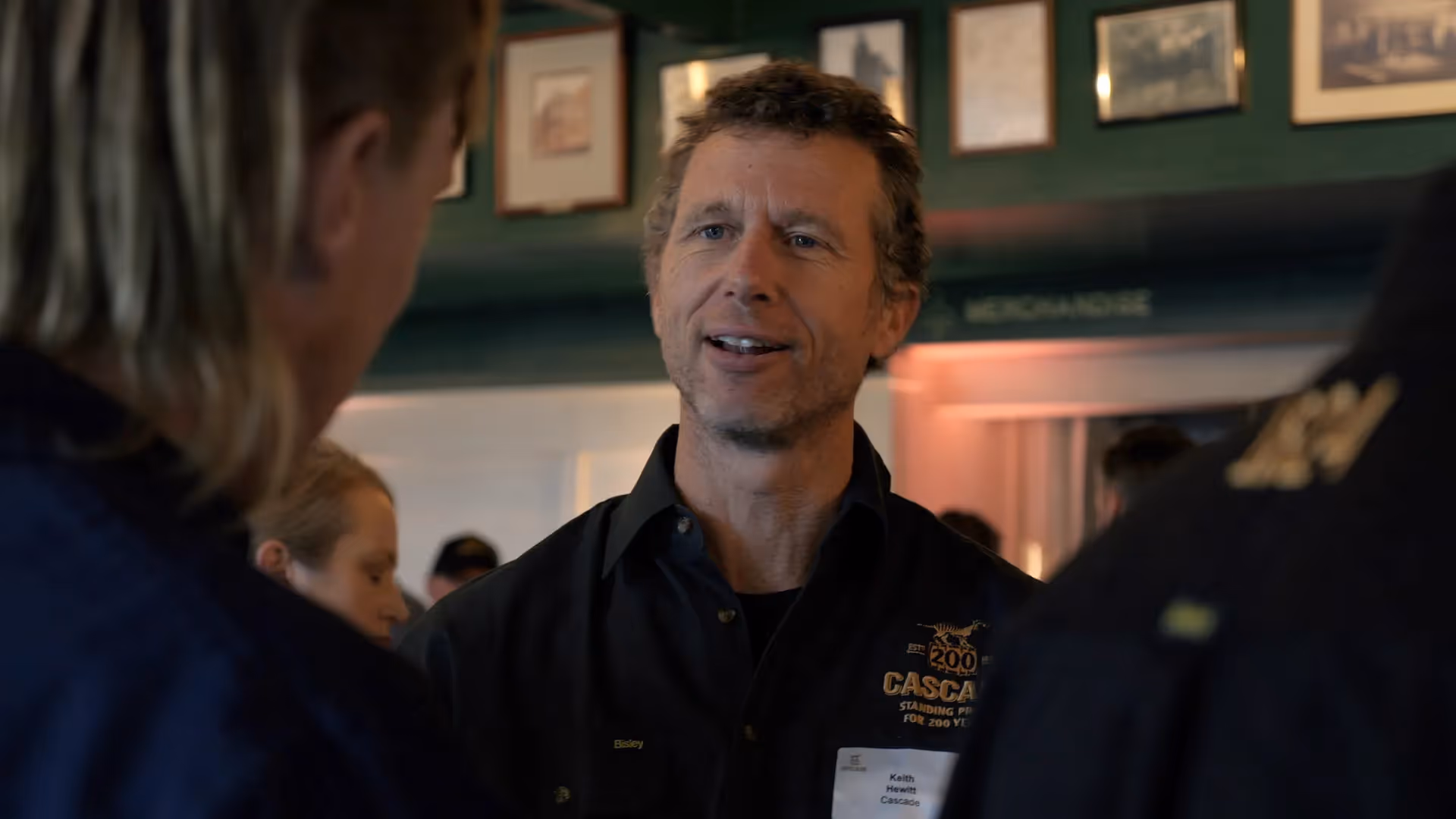 man with short hair stands talking to colleagues at cascade 200th event