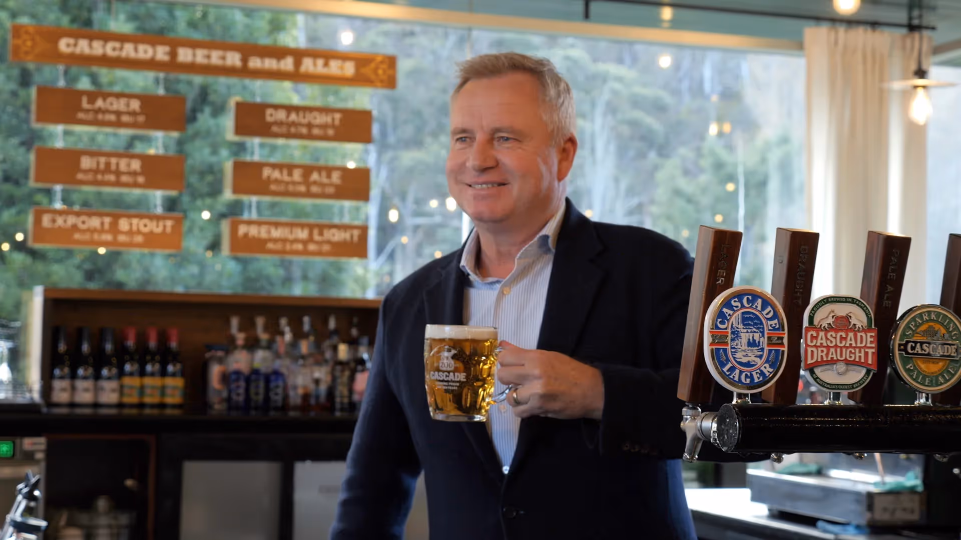 jeremy rockliff standing in blue suit holding beer