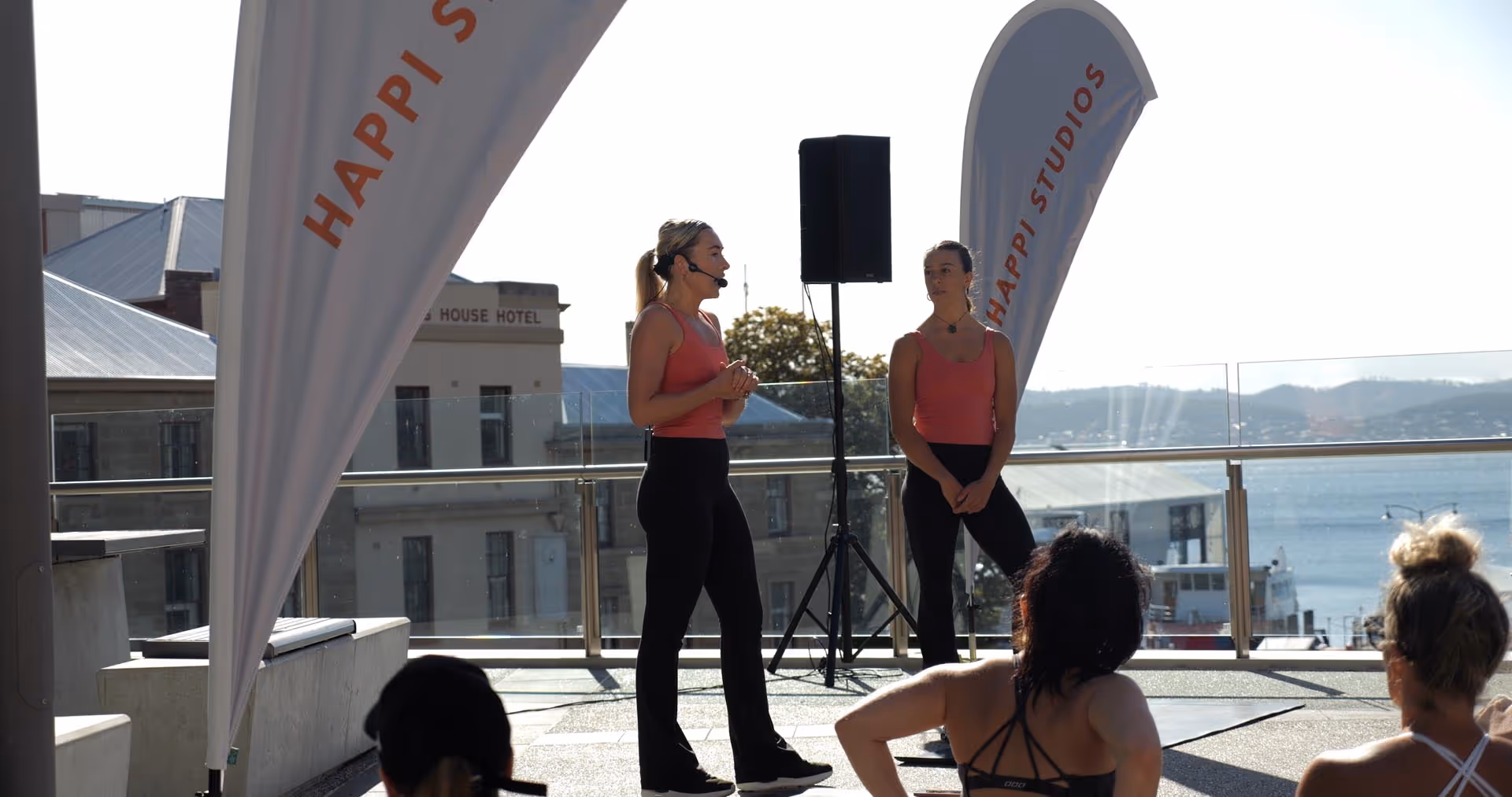 two pilates instructors stand in front of crowd