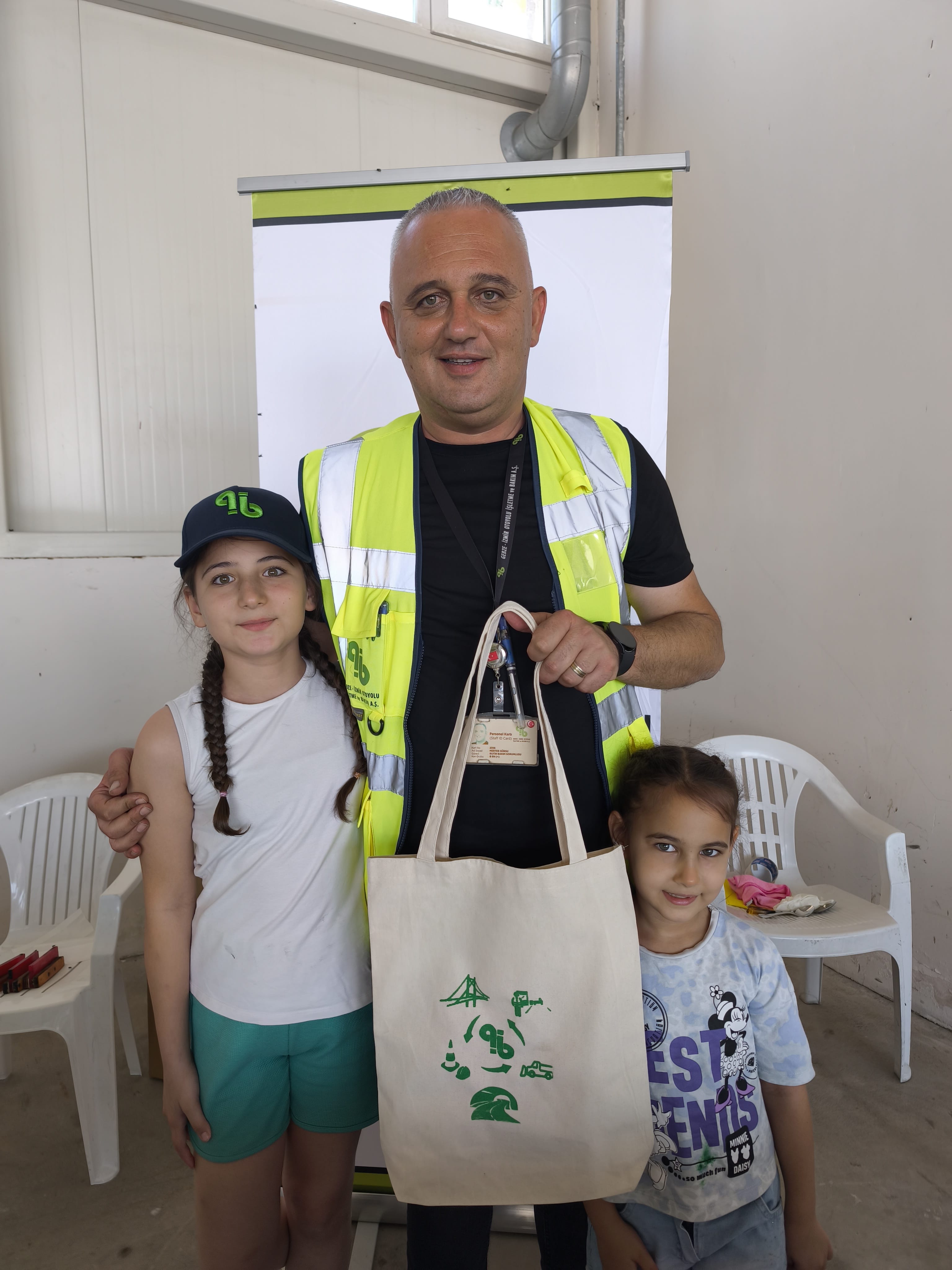 A happy dad with his two daughters having just screen printed their own sustainable tote bags at a corporate team building event
