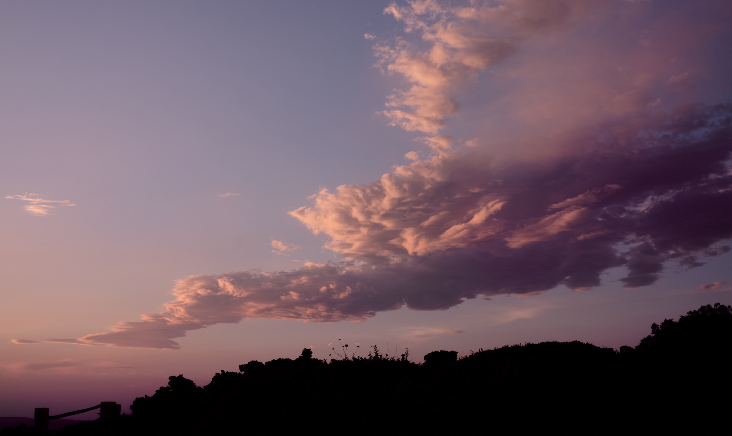 Eine Wolke, die einem Drachen im Sonnenuntergang gleicht, legt sich sanft über die Umrisse der Erde.