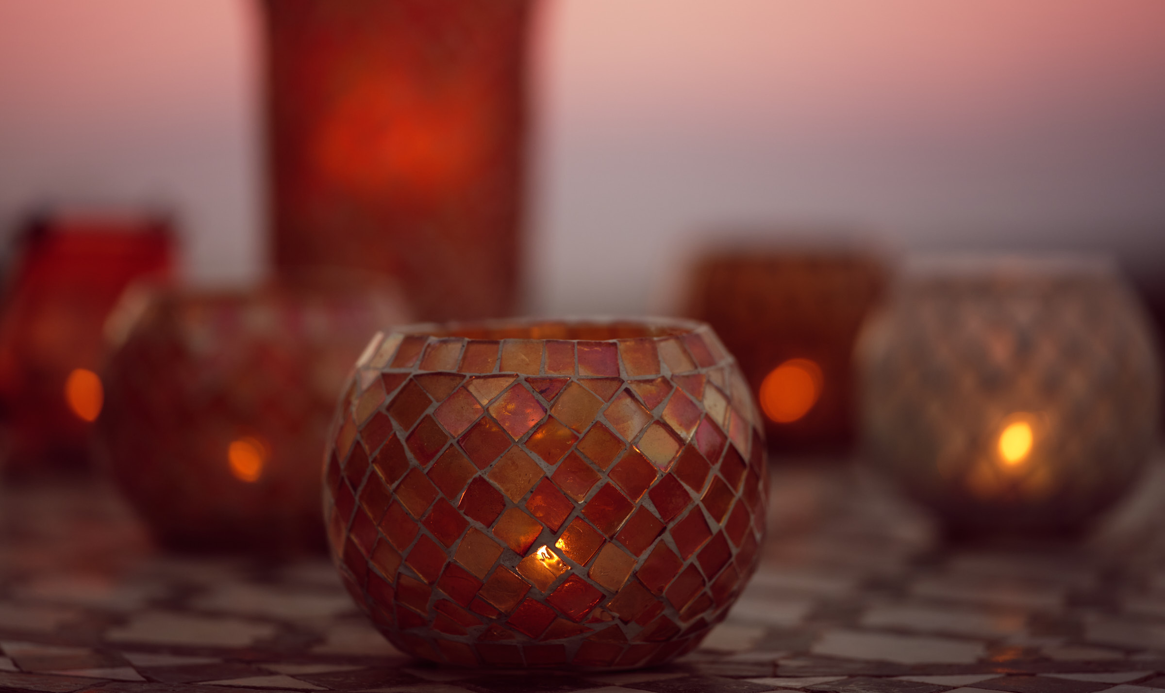 Windlichter aus verschieden-farbigem Glas auf einem Mosaiksteintisch