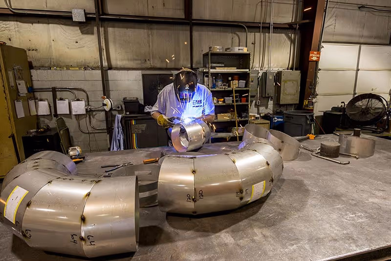 An M&E worker creating pipes out of sheet metal - sheet metal fabrication