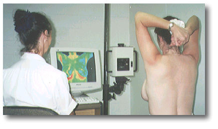 A medical professional analyzes a thermal imaging scan of a patient's upper back and chest displayed on a monitor.