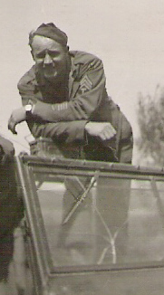 Black and white photo of a man in a military uniform leaning on a railing outdoors.