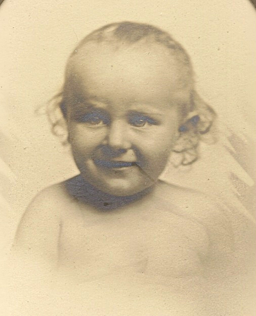 Black and white portrait of a smiling young child with curly hair, looking slightly to the right.