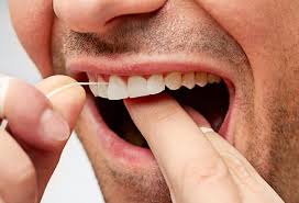 Close-up of a man flossing his upper teeth with dental floss.