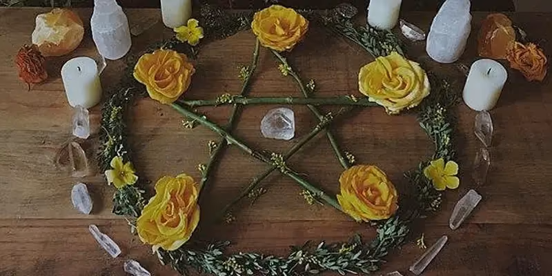 Samhain altar containing a pentagram, candles, and roses