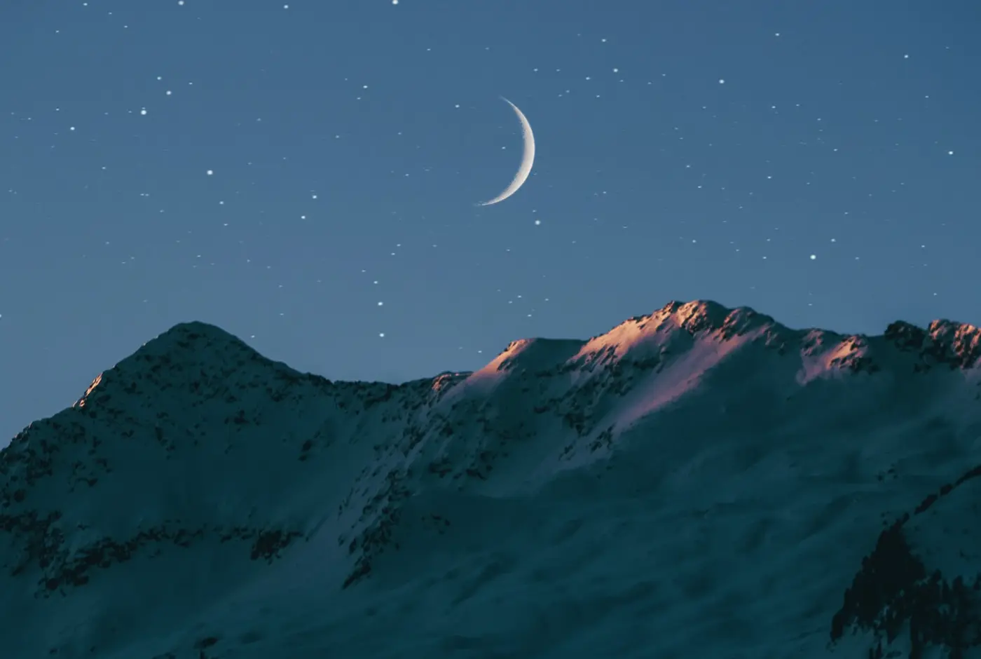 a waning crescent just before a new moon over a mountain range