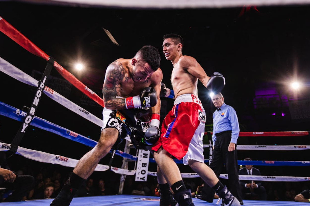 Two boxers engage in a fierce match inside a boxing ring, showcasing their skills and athleticism.  