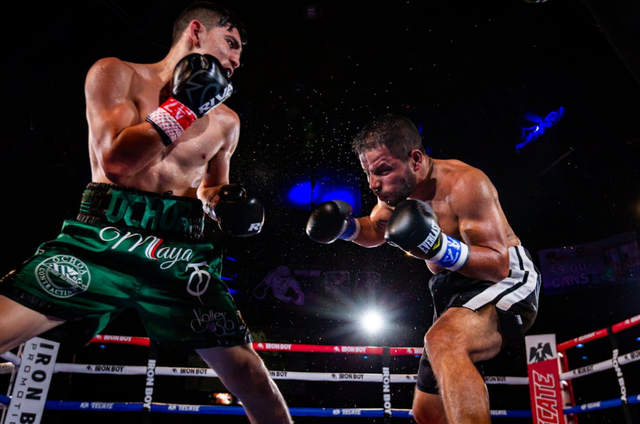 Two boxers engage in a fierce match inside a boxing ring, showcasing their skills and athleticism. 
