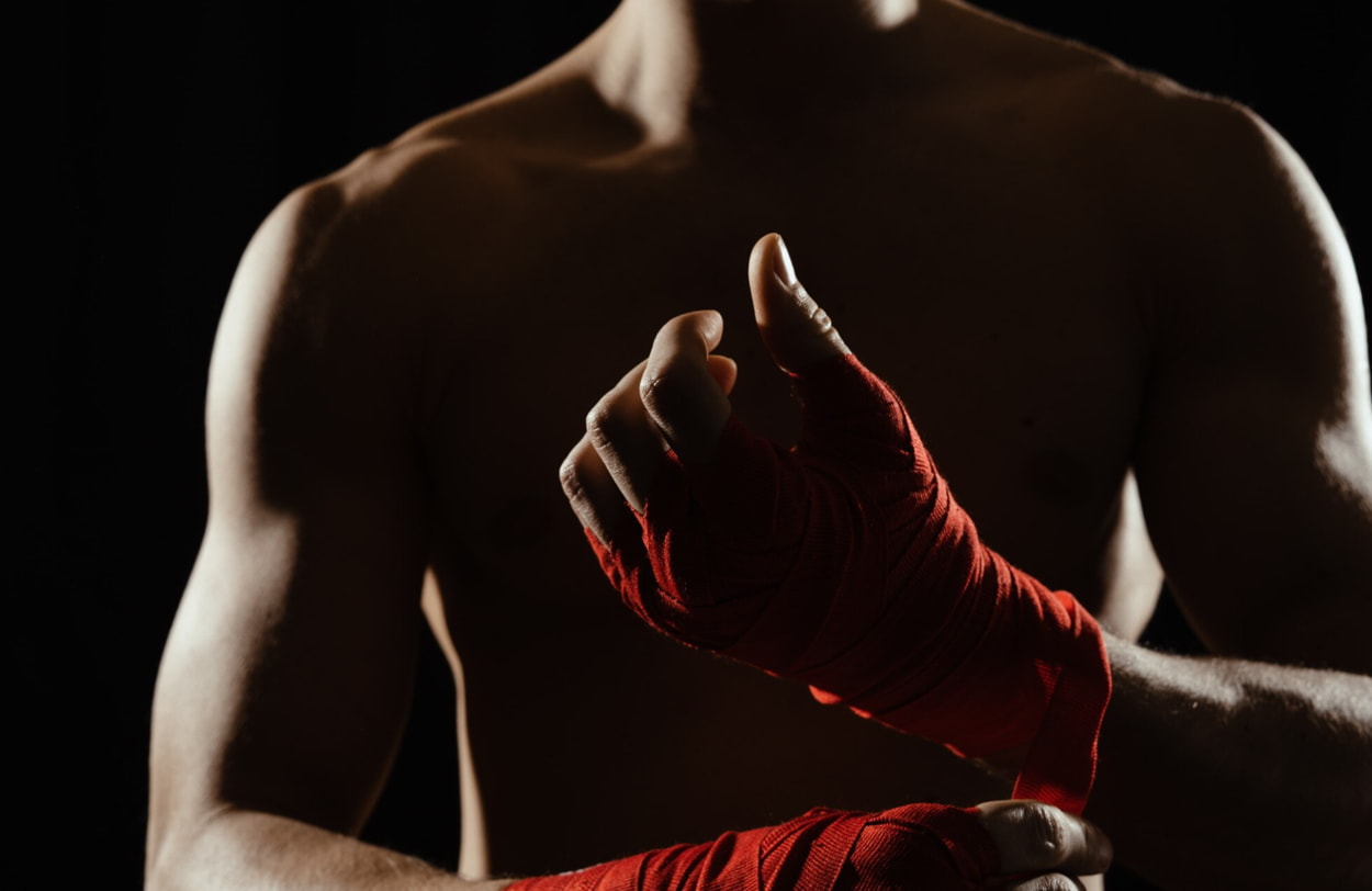 A man wearing red boxing gloves, ready for a match, stands confidently with his fists raised.