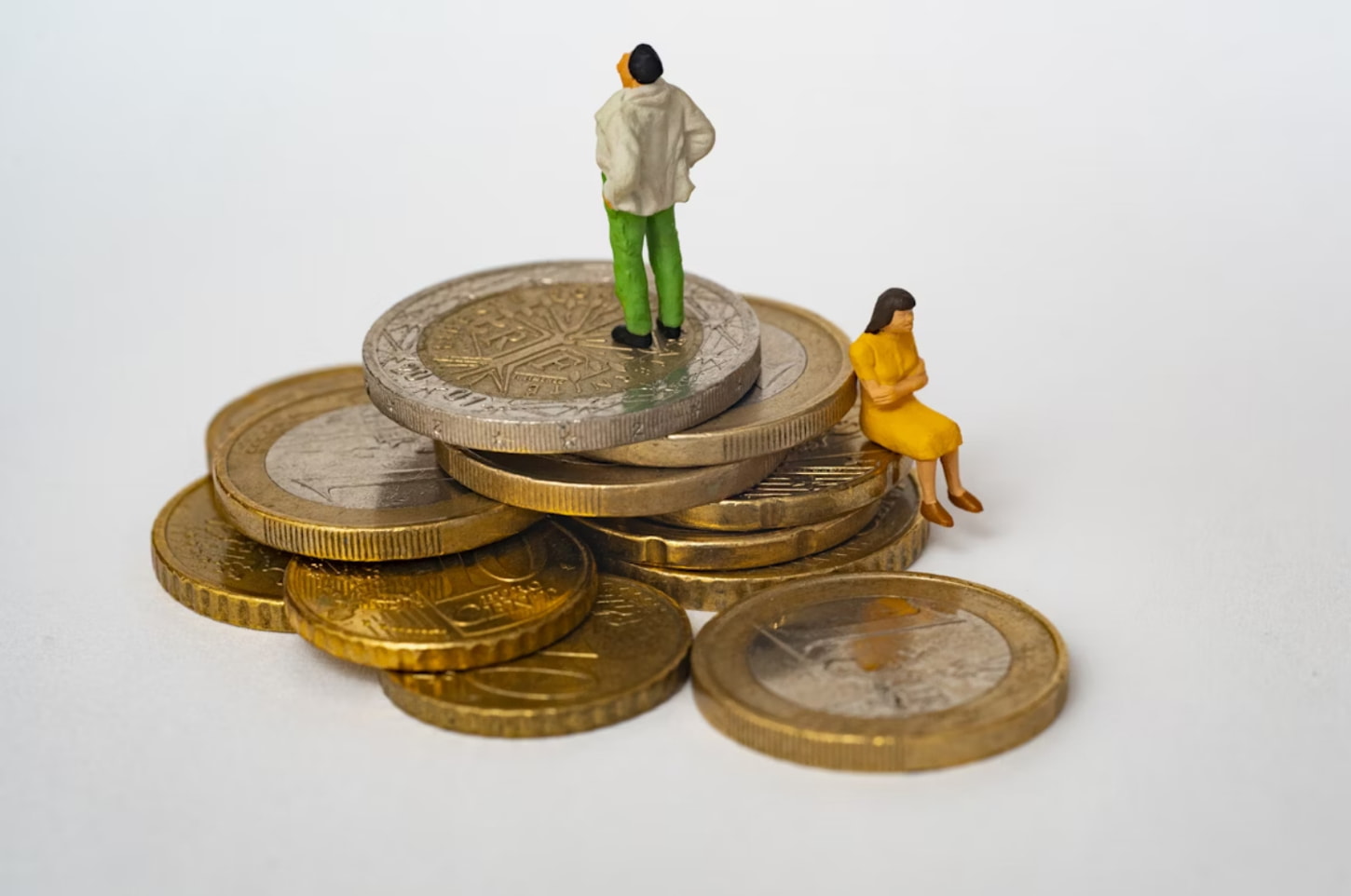 Miniature figures stand atop stacks of euro coins, symbolizing financial growth and economic themes. 