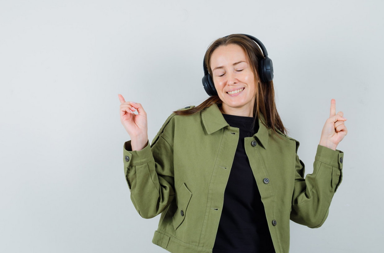 A woman wearing headphones, immersed in listening to music with a focused expression. 