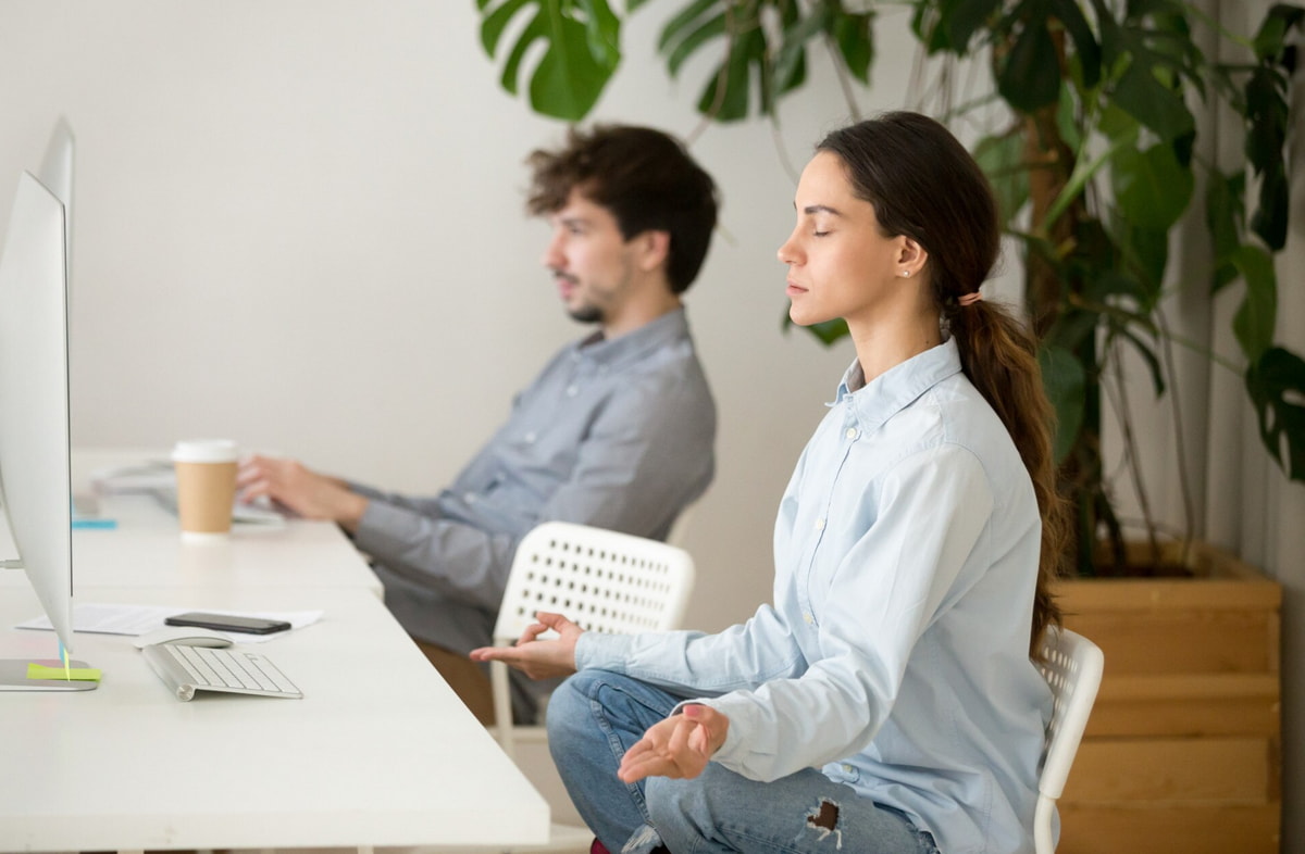A man and woman seated at a desk, focused on a computer screen in a collaborative work environment.
