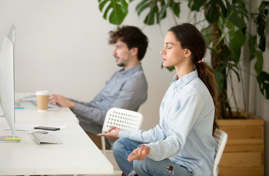 A man and woman seated at a desk, focused on a computer screen in a collaborative work environment. 