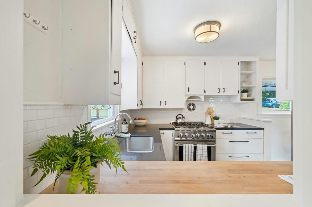 A modern kitchen featuring white cabinets and a sleek black stove, creating a stylish and contemporary atmosphere. 