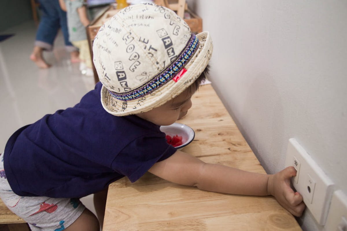 A young child wearing a hat joyfully plays with a colorful toy on the floor. 
