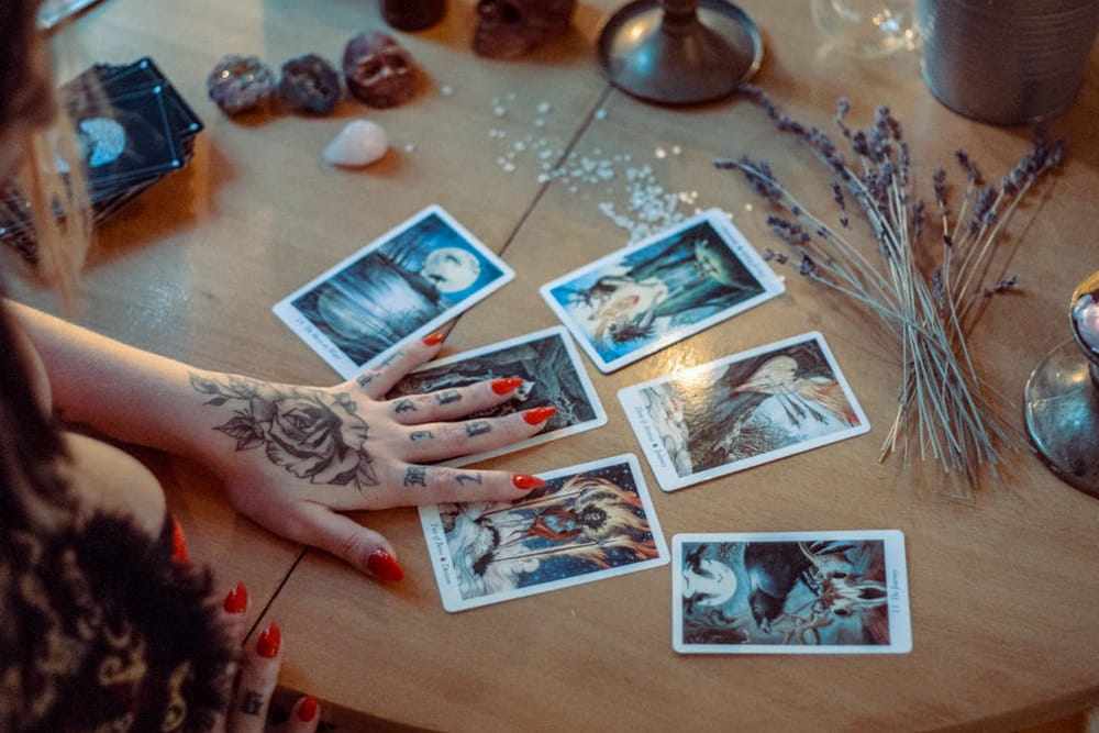 A woman with tattooed hands holds a set of playing cards, showcasing her unique style and personality. 