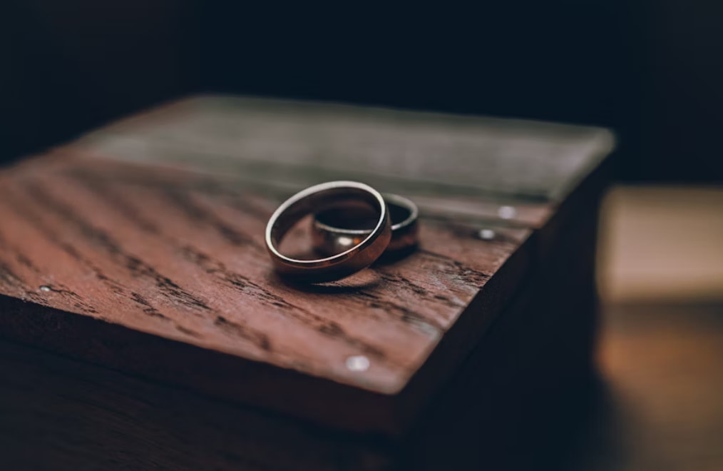 Two wedding rings resting on a rustic wooden box, symbolizing love and commitment. 