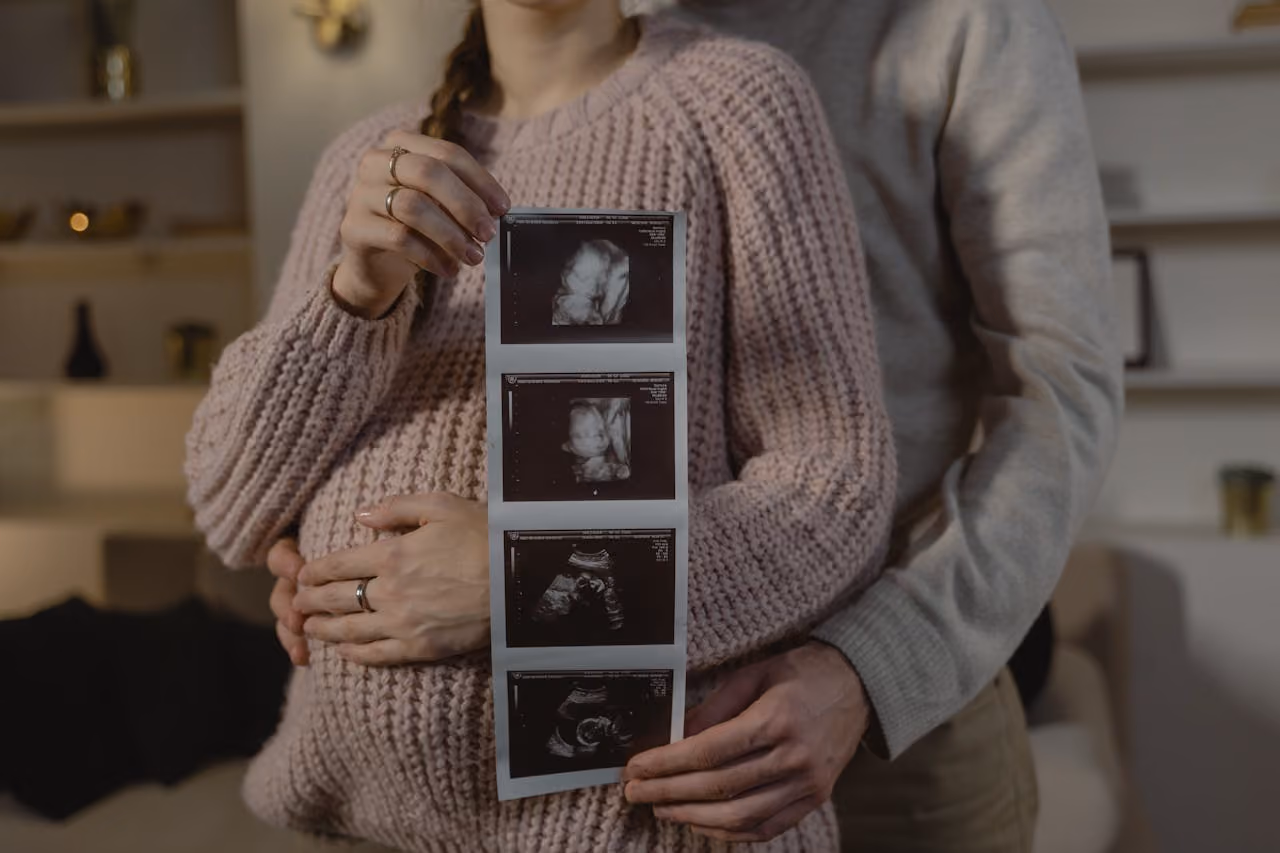 couple posing with sonogram photos