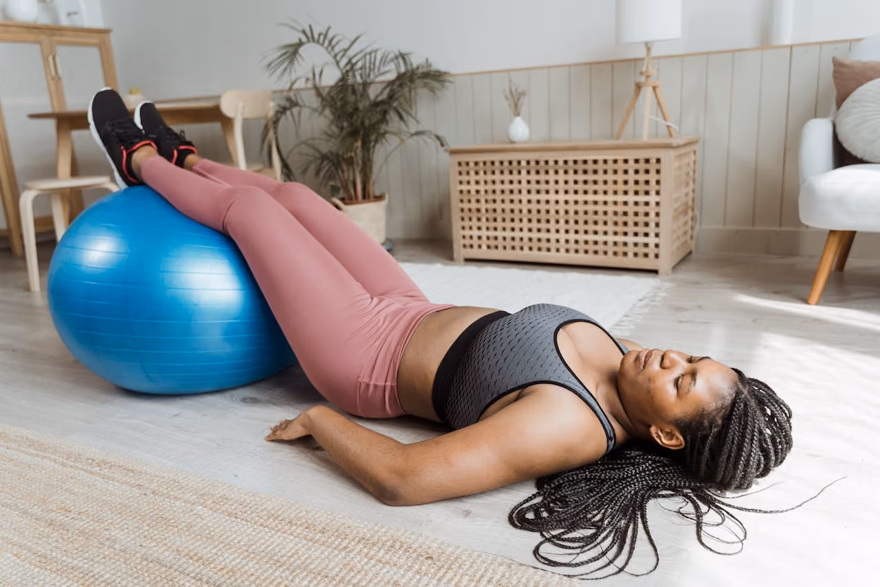 woman in exercise clothes lying with her legs elevated on an exercise ball