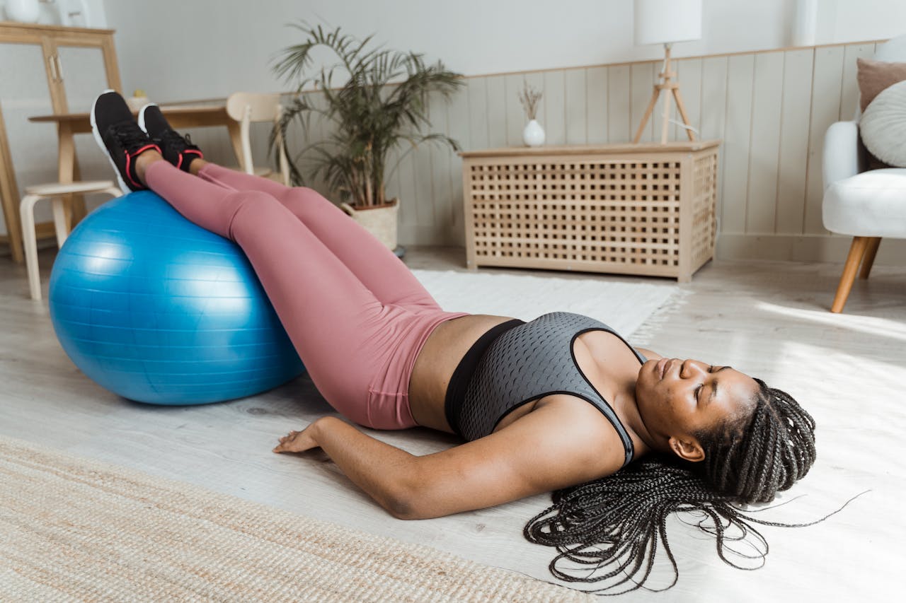 woman in exercise clothes lying with her legs elevated on an exercise ball