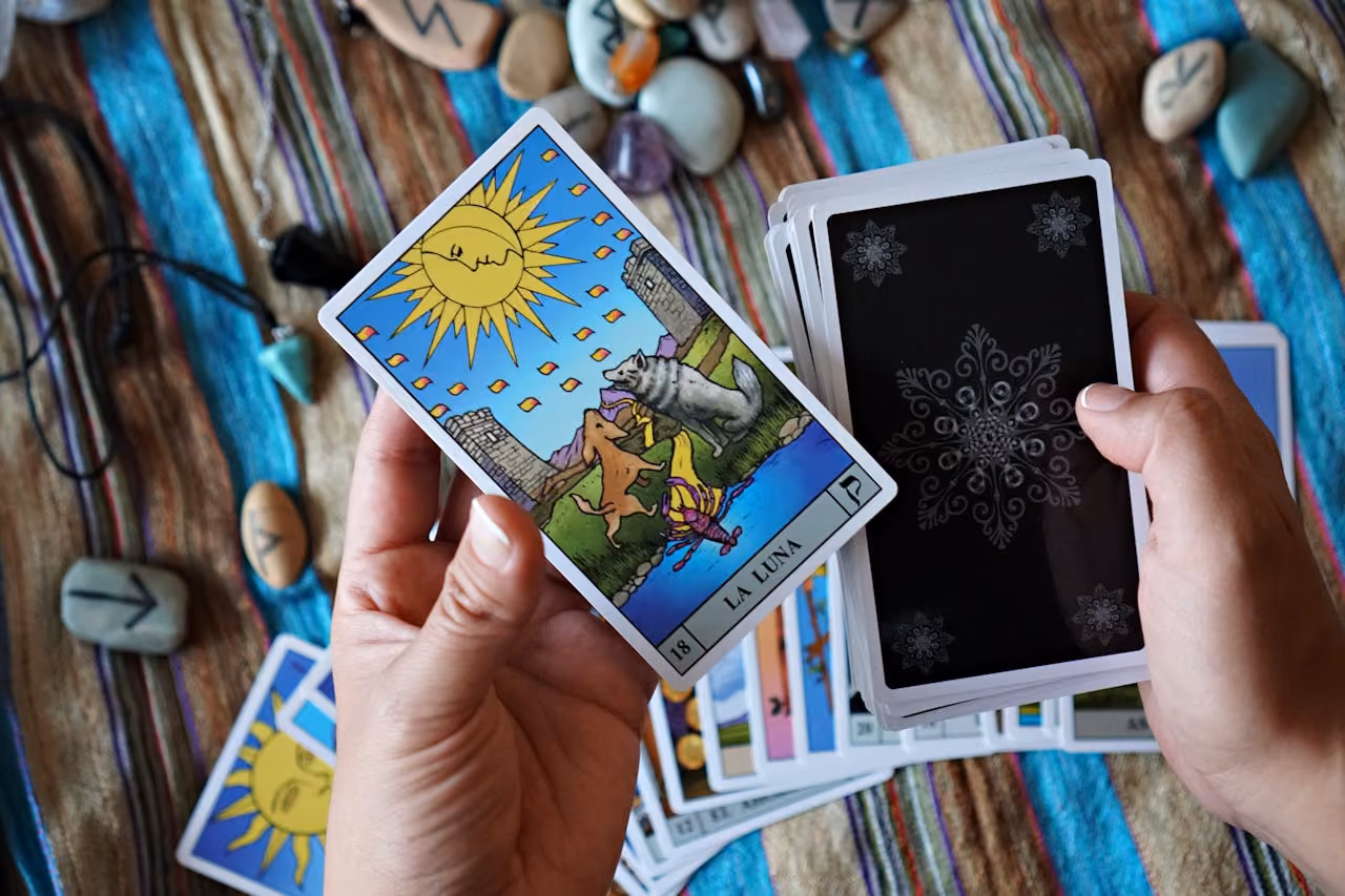 Practitioner flipping through a deck of Tarot cards with The Moon on the top of the stack