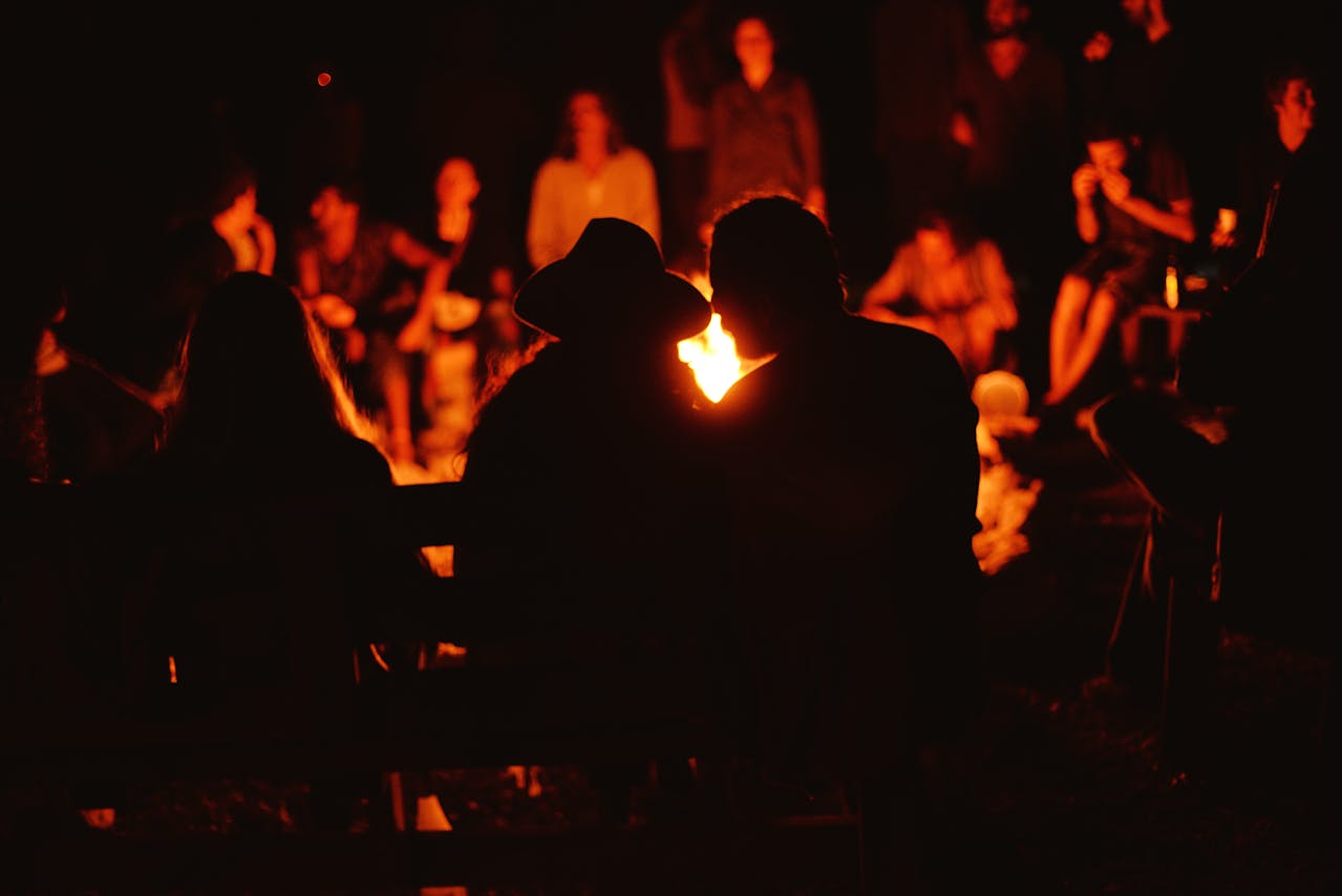 Community gathered around a glowing bonfire, singing, eating food, and celebrating Beltane