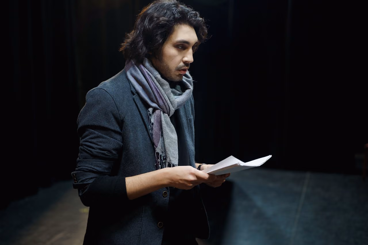 man on stage practicing for a performance, suffering from stage fright due to an energetic creative block keeping him stuck in anxiety instead of being free to express himself