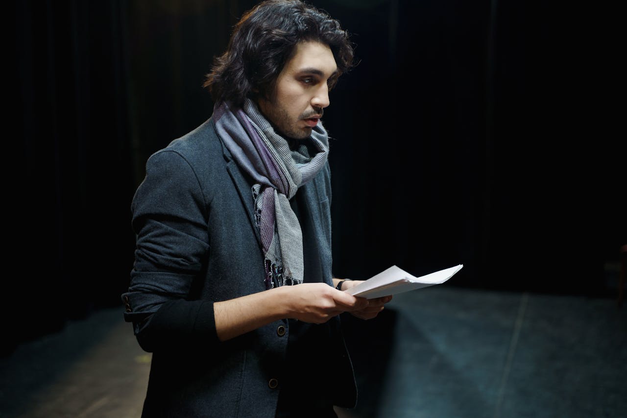 man on stage practicing for a performance, suffering from stage fright due to an energetic creative block keeping him stuck in anxiety instead of being free to express himself