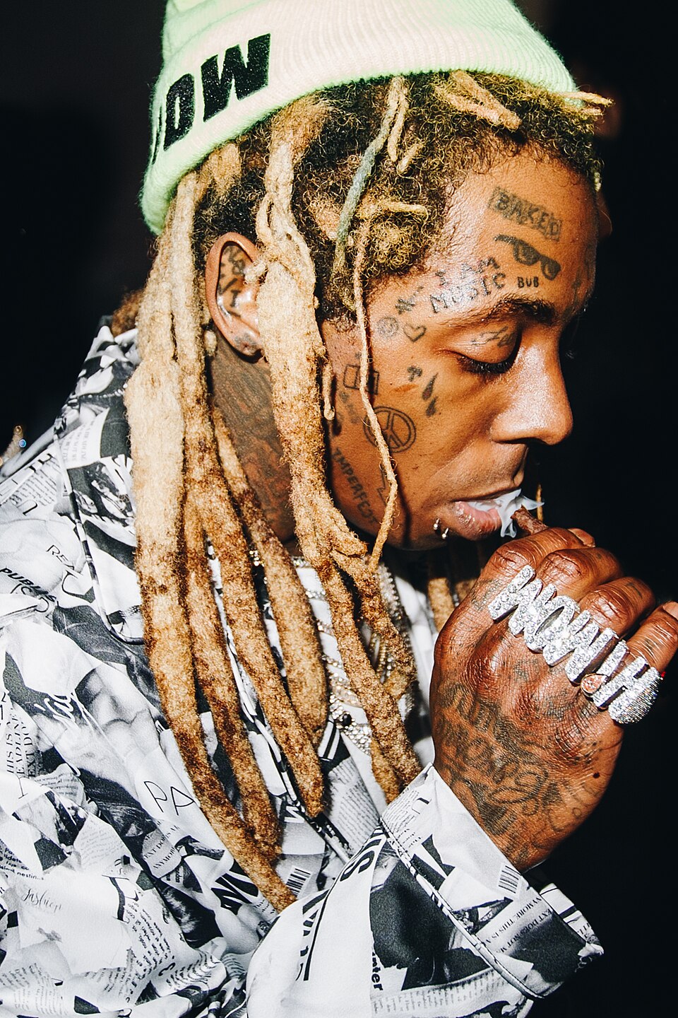 a close up of Lil Waynes face in profile, showing some of his iconic face tattoos including Bub, Baked, I am music, teardrops, and hearts