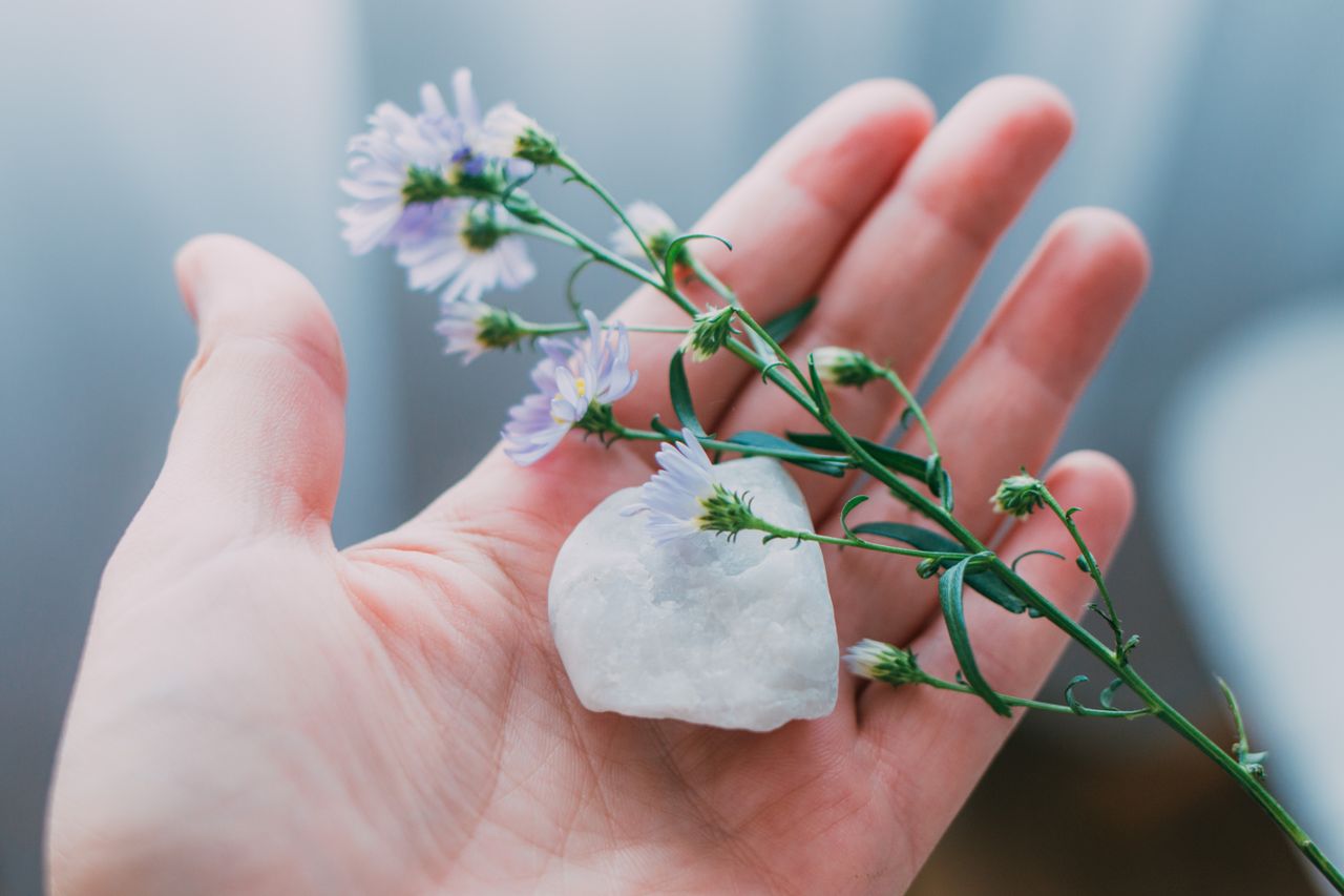 woman holding moonstone in her palm, contemplating the spiritual meaning of the stone