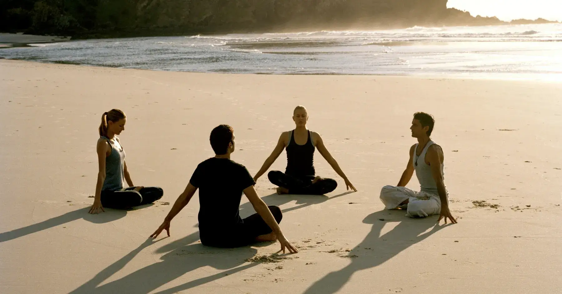 people seated on the beach in a meditation circle