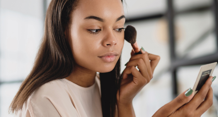 woman applying blush to her face
