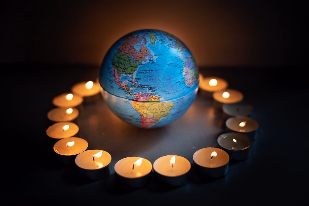 small model globe surrounded by flickering tealight candles, representing how earth, water, fire, and air must exist in balance together