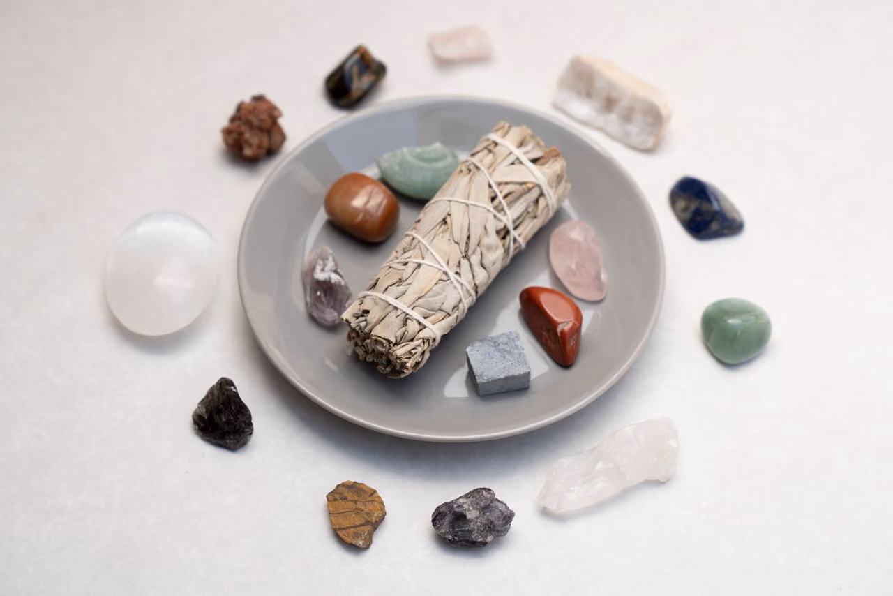 sage smudge stick in a shallow dish surrounded by crystals, which it will be used to clear energy from
