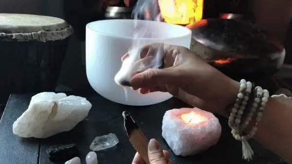smudging various crystals and objects with a strip of palo santo bark