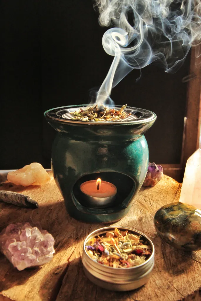 loose incense smoldering in a ceramic wax warmer with a fine metal mesh grate placed over the top