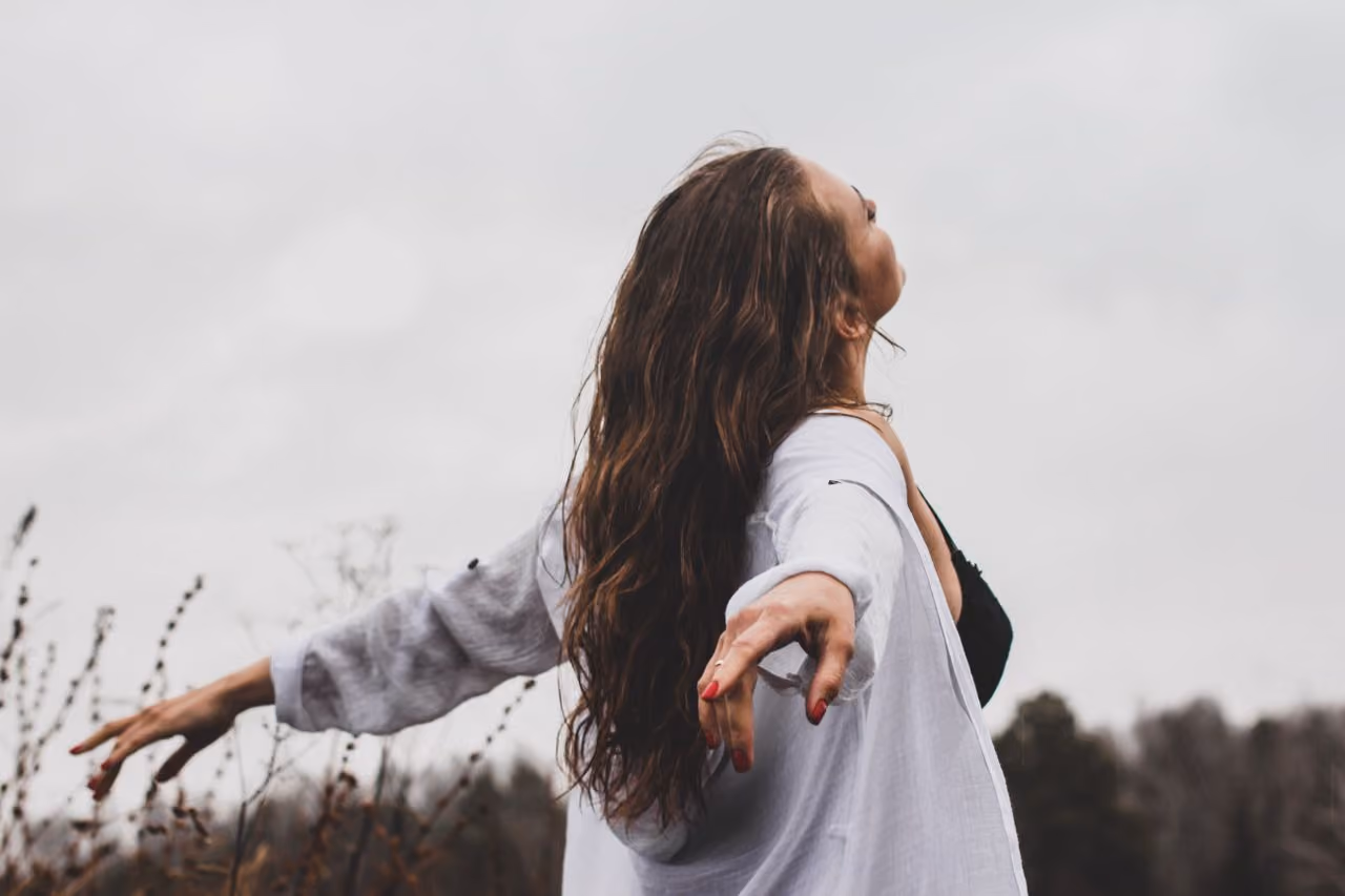 woman with her head back and arms open to the spiritual experience of feeling the air