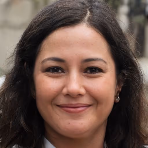 Close-up of a woman with dark hair smiling gently, outdoors with blurred background.