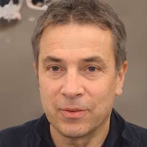 Middle-aged man with short grayish hair wearing a dark jacket against a plain background.